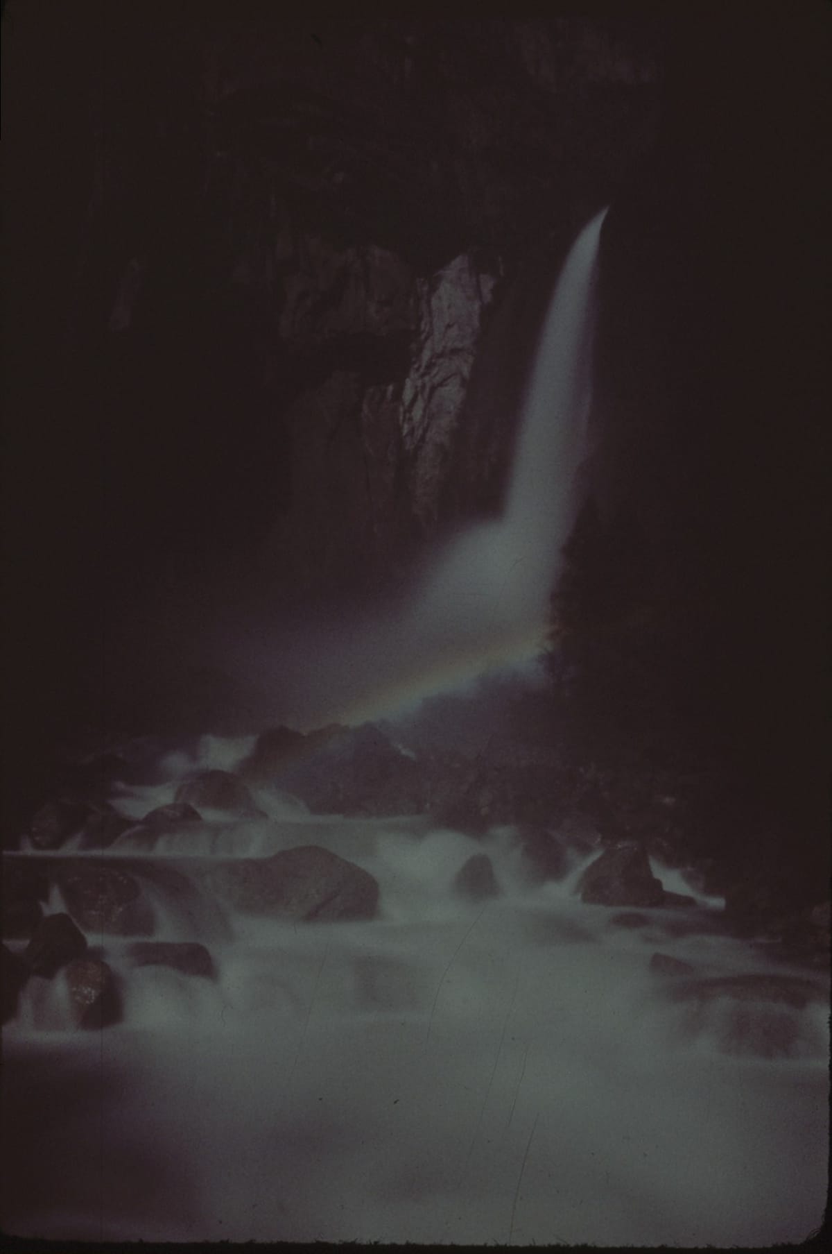 어두운 Lower Yosemite Fall 앞의 물안개에 걸린 희미한 달빛 무지개